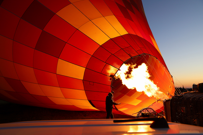 Fire of a bright yellow flame that comes from the burner into a ball of cloth, a red ball, inflating it to take off into the sky.