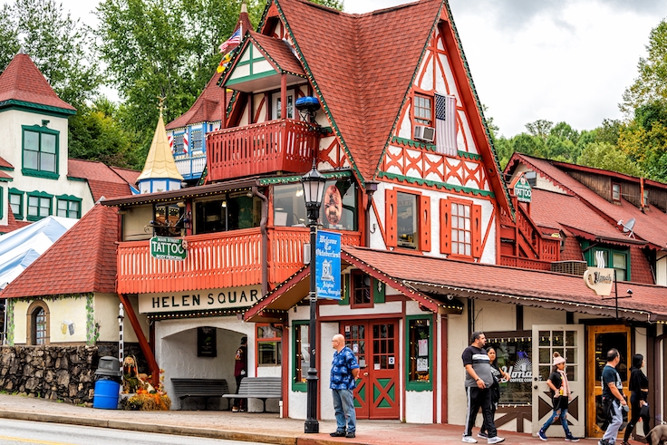 Helen, USA - October 5, 2021: Helen, Georgia Bavarian village traditional architecture house building with sign for Helen square on Main street with red roof tiles and people