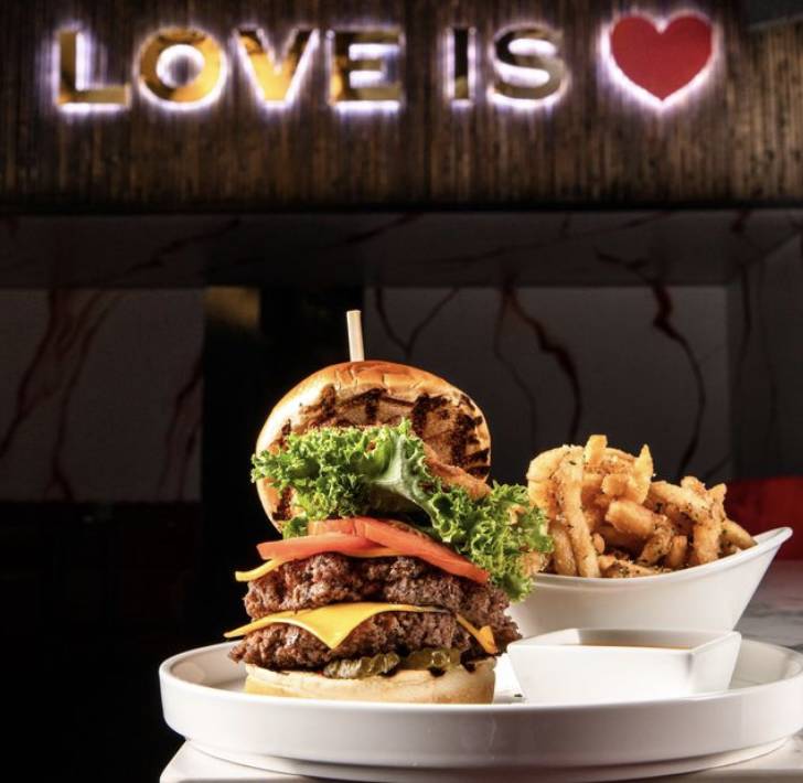 a huge burger with "love is" above it