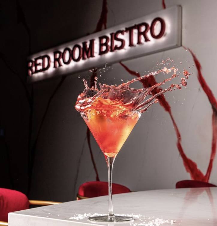 a beautiful red cocktail splashing out of the glass