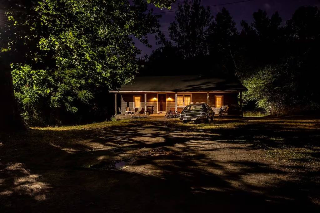 exterior of an 80s style house with a broken down car parked in the driveway