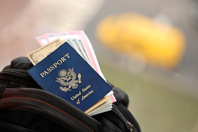 Blue United States of America passport with money and airline tickets on touristic backpack close up. Tourism and travel concept