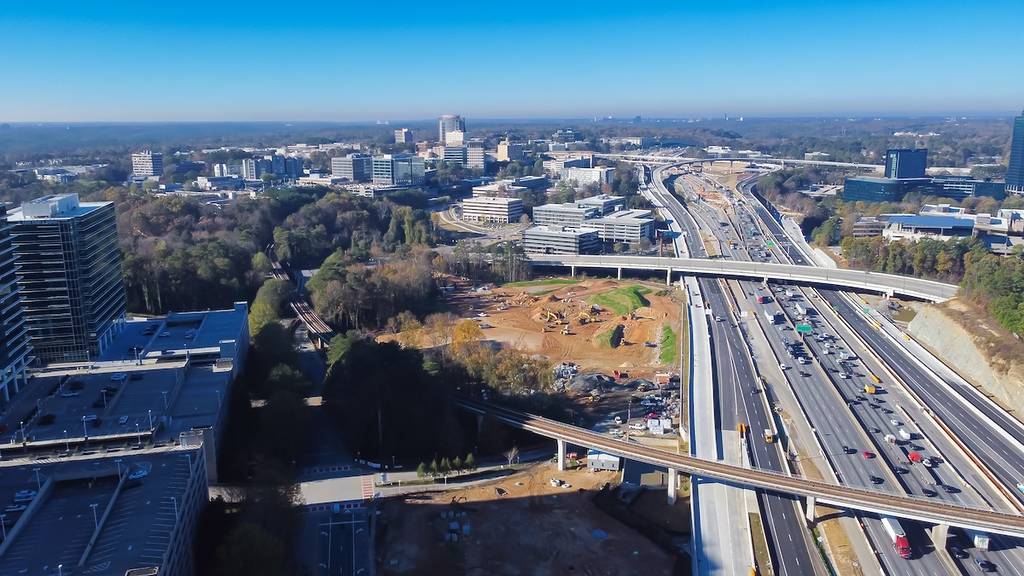 Rapid transit line rail system, elevated expressway along Perimeter Interstate 285 highway construction site, skylines office towers of Perimeter Center, Atlanta, Georgia. Aerial view metro complex