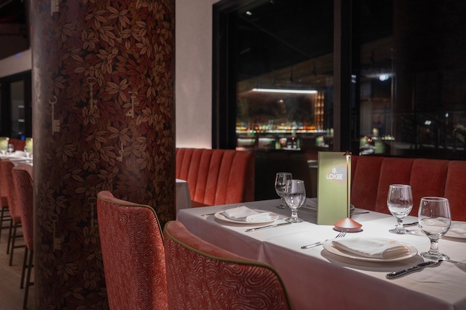 a fancy dining table with a green menu and nice wine glasses