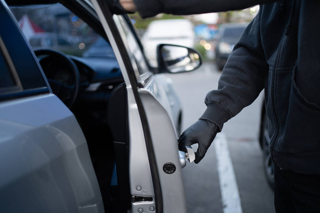 Primer plano de un ladrón con camisa negra y guantes negros. Intentó abrir la puerta del coche y tratar de entrar. concepto de robo de coche.