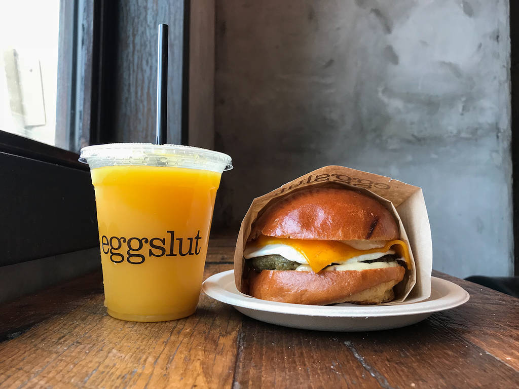 a cup that says eggslut on it with a sandwich beside it