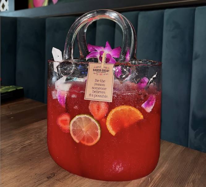 a glass purse full of pink alcohol and fruit