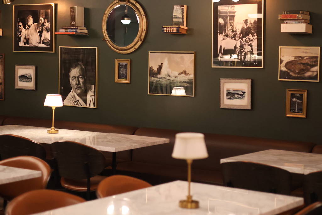 una pared verde oscuro llena de fotos de Hemingway