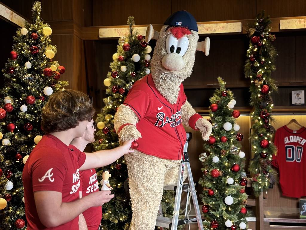 La mascota de los Braves, BLOOPER en una escalera rodeado de árboles de Navidad