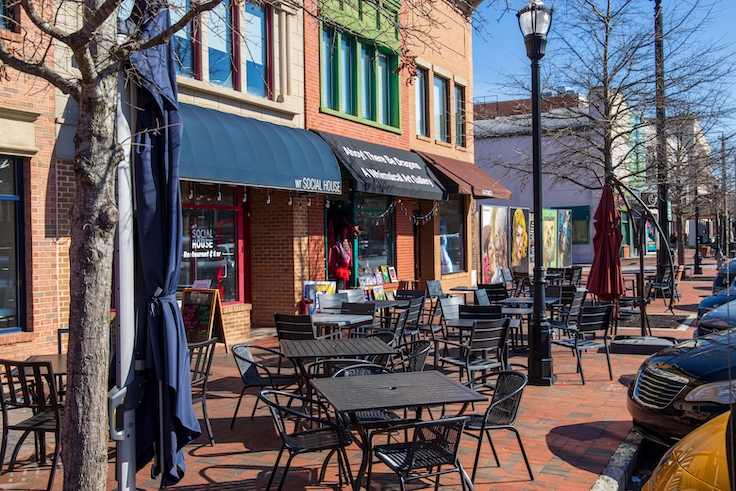 Marietta, Georgia USA - 2 4 2023: a red brick sidewalk lined with shops, restaurants and bars with tables and chairs on the sidewalk, parked cars and a gorgeous clear blue sky in Marietta Georgia USA