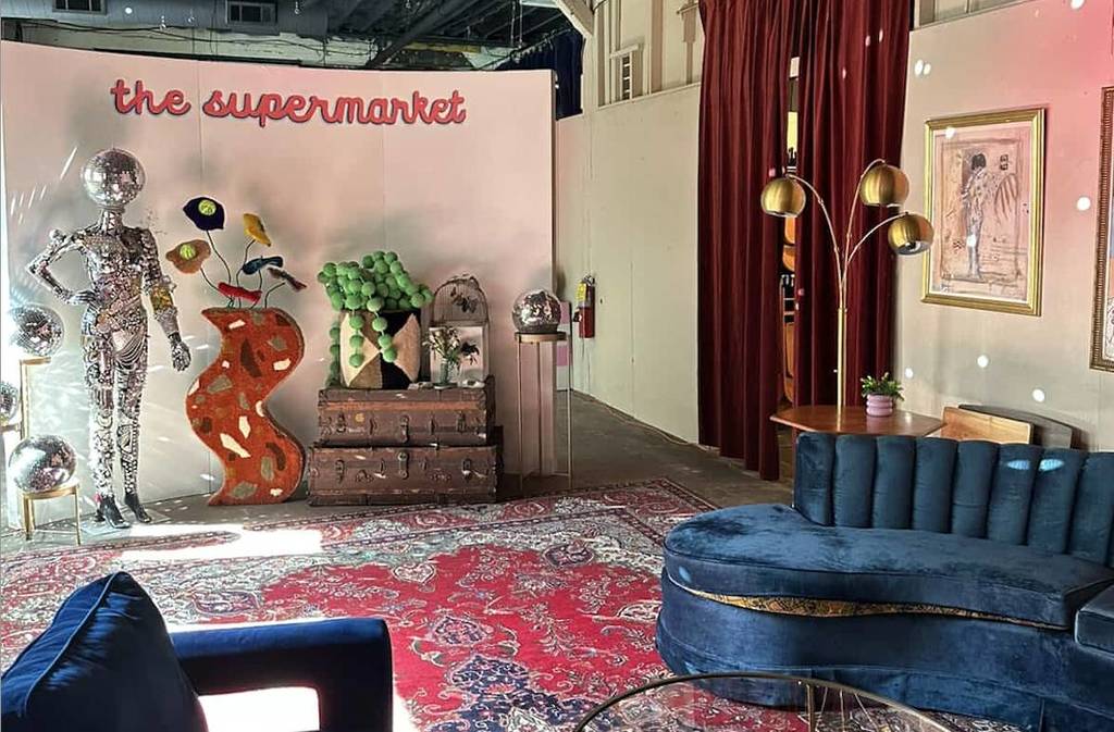 a cute art studio with a blue velvet couch, red curtains and a large Persian rug