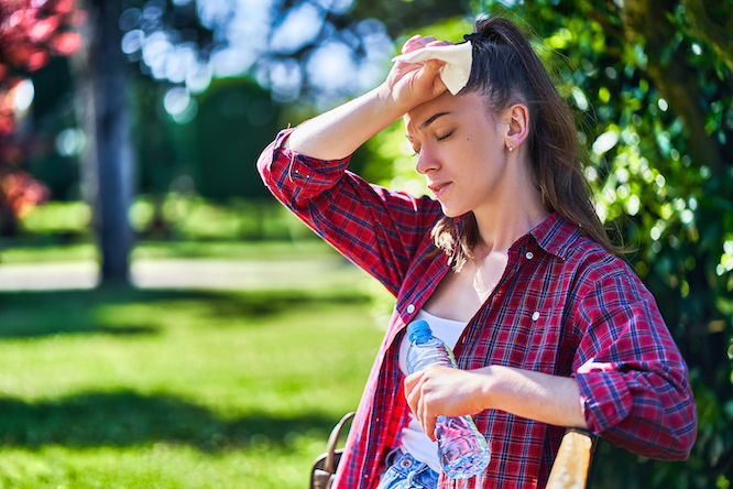 woman hot in a field with a bottle of water