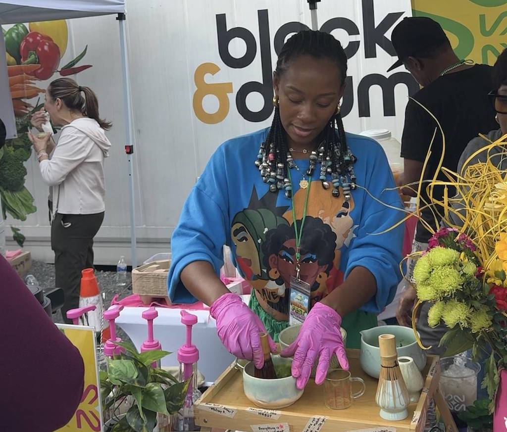 a woman at a fancy yellow and green matcha pop up with flowers and bright colors