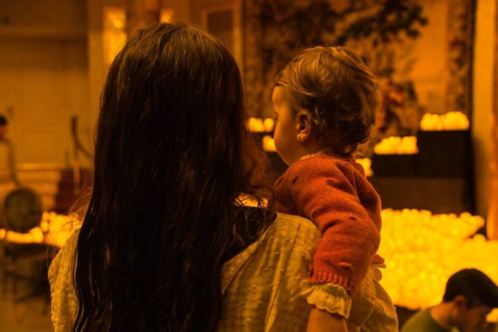 A mother holding her baby in her arms as they enjoy a Candlelight concert