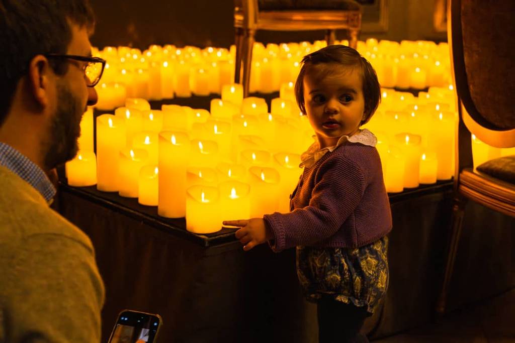 A little baby touching Candlelight's flameless candles as her father takes pictures during a Candlelight concert