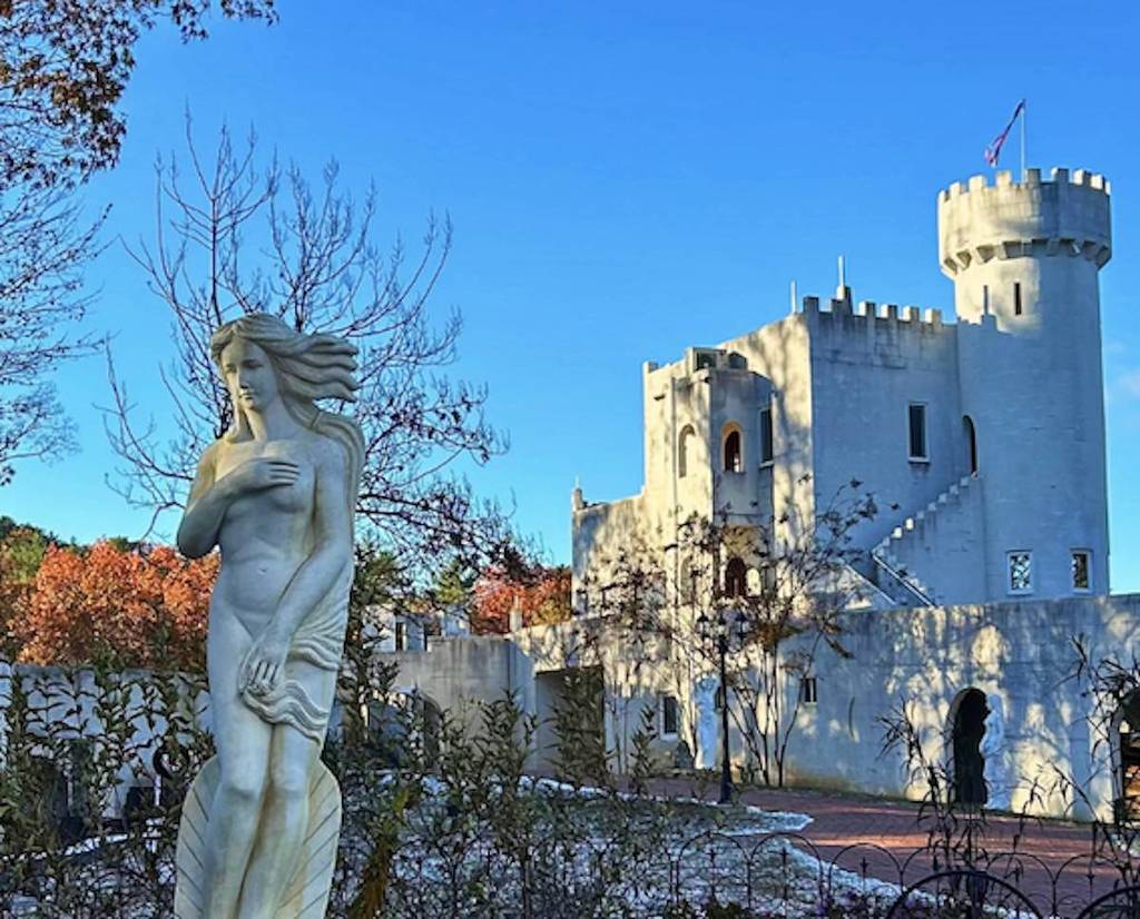 beautiful castle with a blue sky and a woman statue in the front