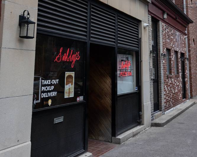 a screenshot of Sally's pizzeria, a dark entrance with Sallys on the door in red