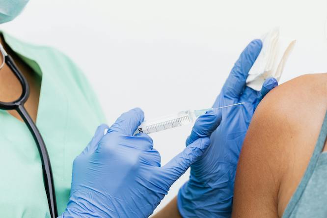 a doctor's gloved hand administering a flu shot