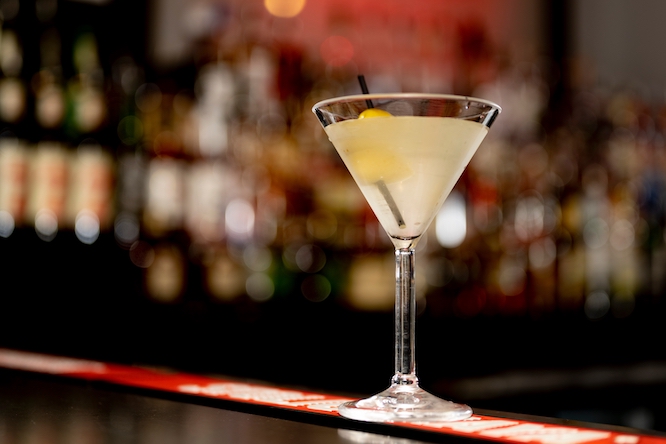 a dirty martini at a nightclub on the bar in front liquor in the background