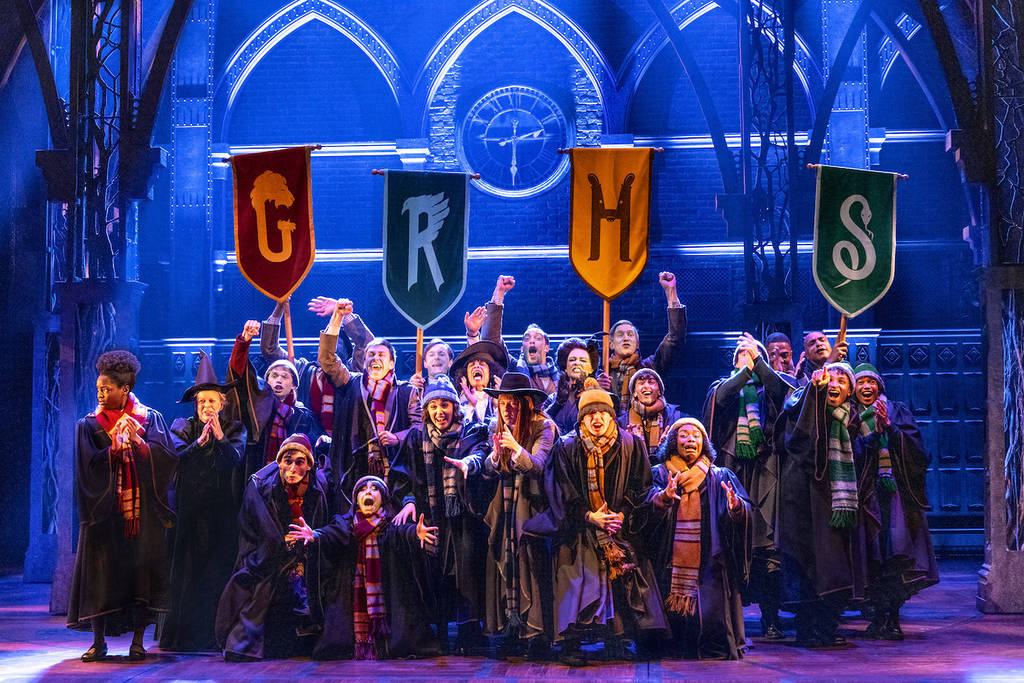 a stage play of Harry Potter with a bunch of Hogwarts students and their house flags