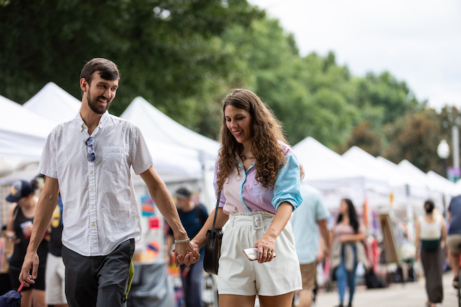 a white couple holds hands at a festival