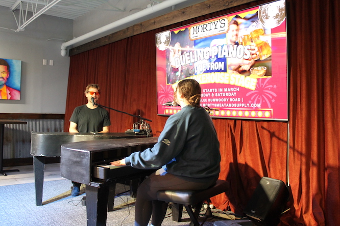 dueling pianos in front of a red curtain