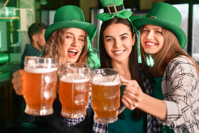 Jóvenes celebrando el Día de San Patricio en un pub con cerveza.
