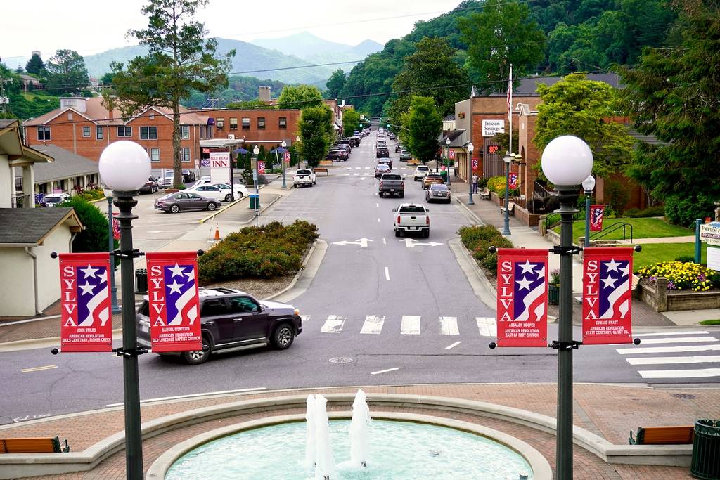Sylva, North Carolina - 2021: View from historic Courthouse stairs. Fountain and West Main Street. Blue Ridge Inn, Wells Fargo Bank, Sylva Police Department. Blue Ridge Mountains surround the town.