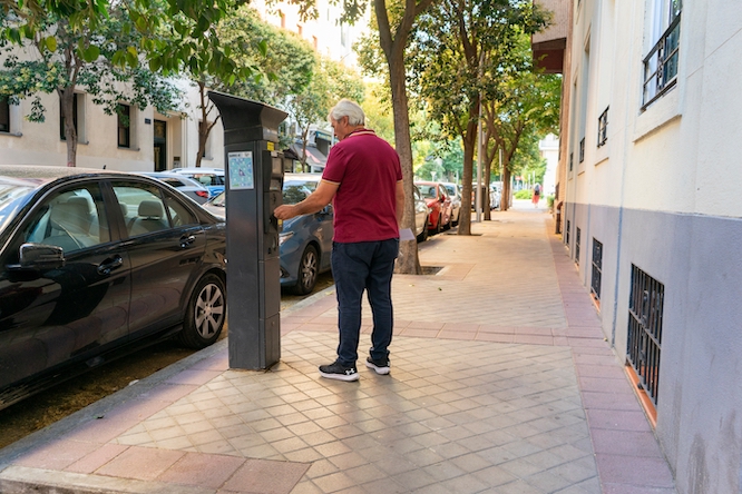 Madrid Central, Spain - July 11, 2024: Elderly person taking a ticket from a parking meter in the community of Madrid Spain