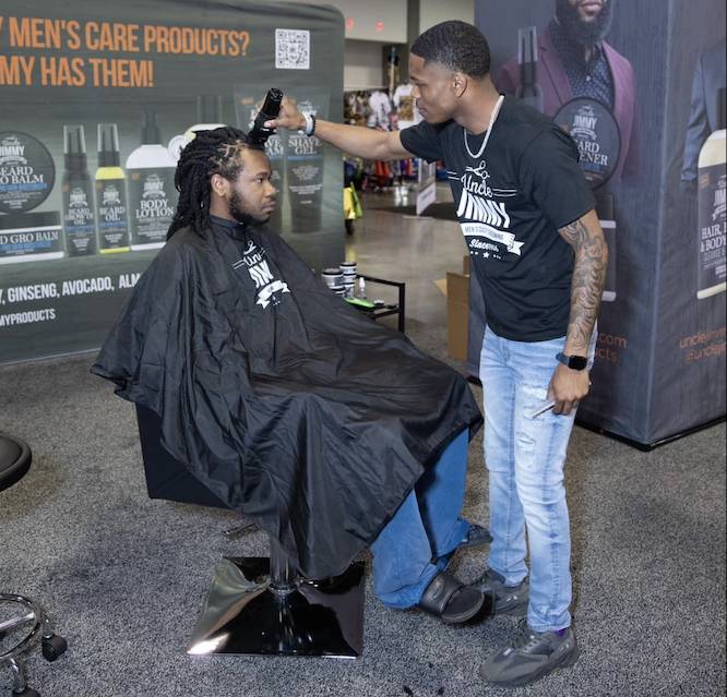 Un peluquero negro cortando el pelo a un hombre negro en una silla de peluquería