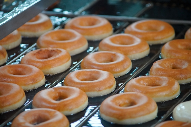 Raleigh, North Carolina - August 7 2025: Krispy Kreme Doughnuts Original Glazed Donuts Conveyor Belt Assembly Line Cooking Process Deep Frying And Glazing