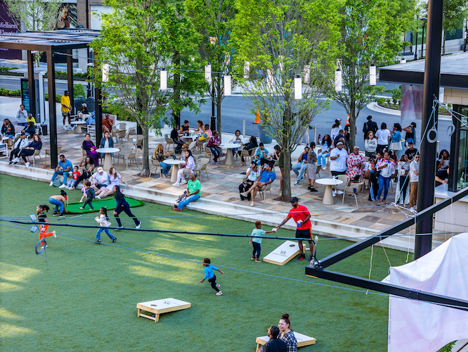 a huge lawn with people playing corn hole