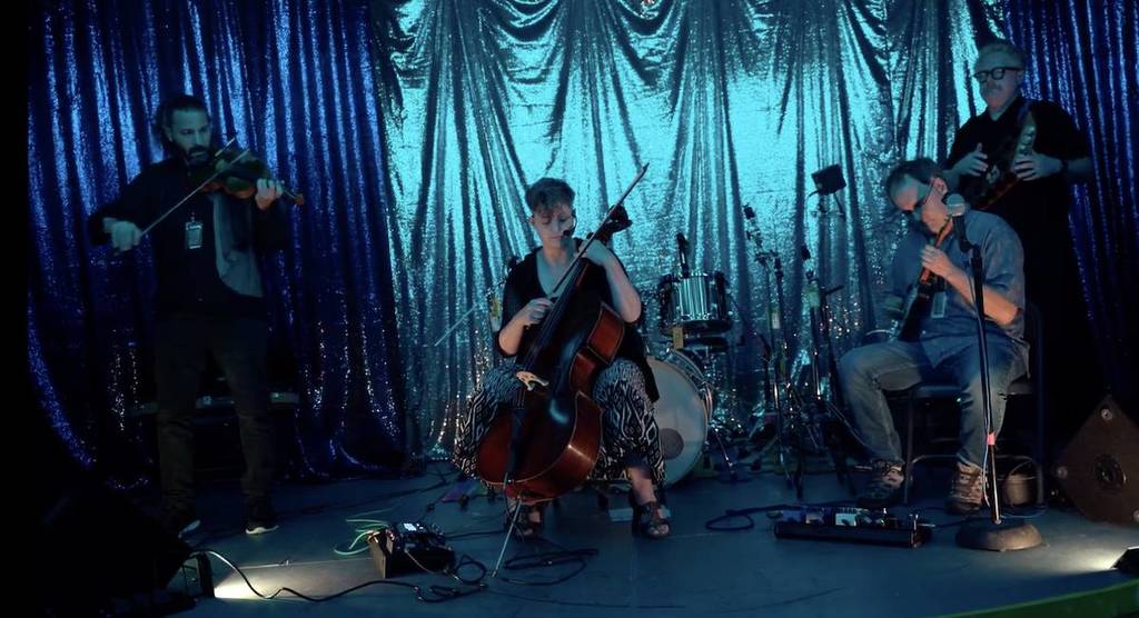 someone playing a cello in front of a blue curtain