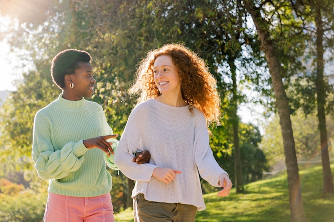 two young women smiling and talking during a walk