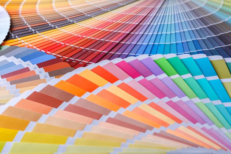 Rueda de colores para elegir el tono de la pintura. Mesa de trabajo de pintor y decorador con el proyecto de la casa, muestras de color, rodillo y brochas.