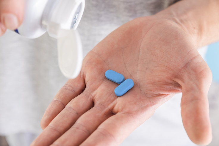 Man pouring PrEP blue pill from medical bottle in a hand. HIV prevention using Pre-Exposure Prophylaxis medicine. Men health. AIDS prevention concept