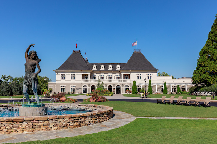 un precioso cielo azul sobre un viñedo del Chateau con una estatua magnífica en la entrada