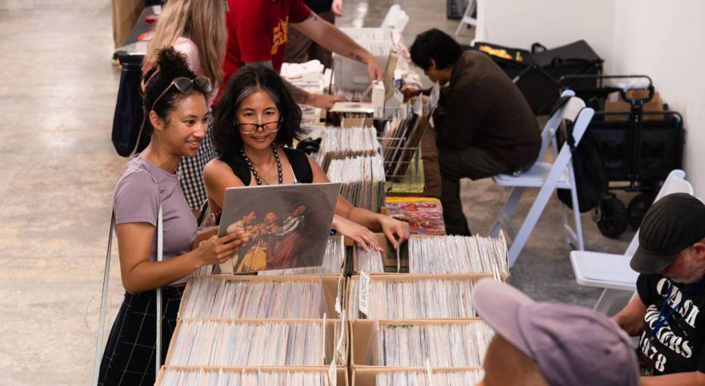 dos personas con montones de discos de vinilo