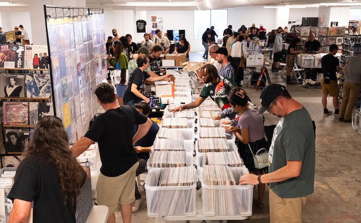 dos personas con montones de discos de vinilo