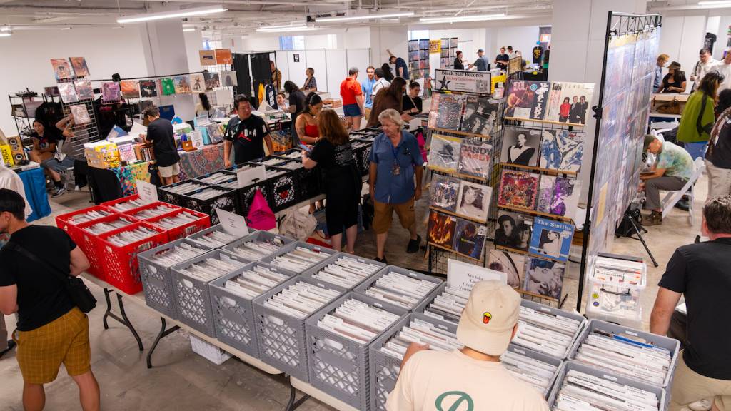 dos personas con montones de discos de vinilo