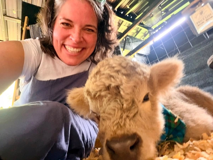 una mujer acurrucándose con una vaca de las Highlands
