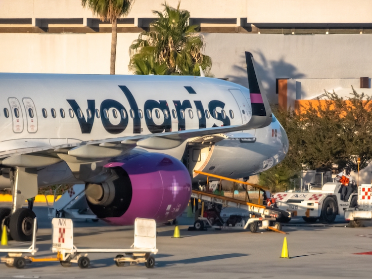 Los Cabos, B.C.S., México. 26 de noviembre de 2024. Primer plano de un Airbus A321 de Volaris estacionado en una puerta de embarque del aeropuerto, con el personal de tierra preparando el avión para su salida desde el Aeropuerto Internacional de Los Cabos.