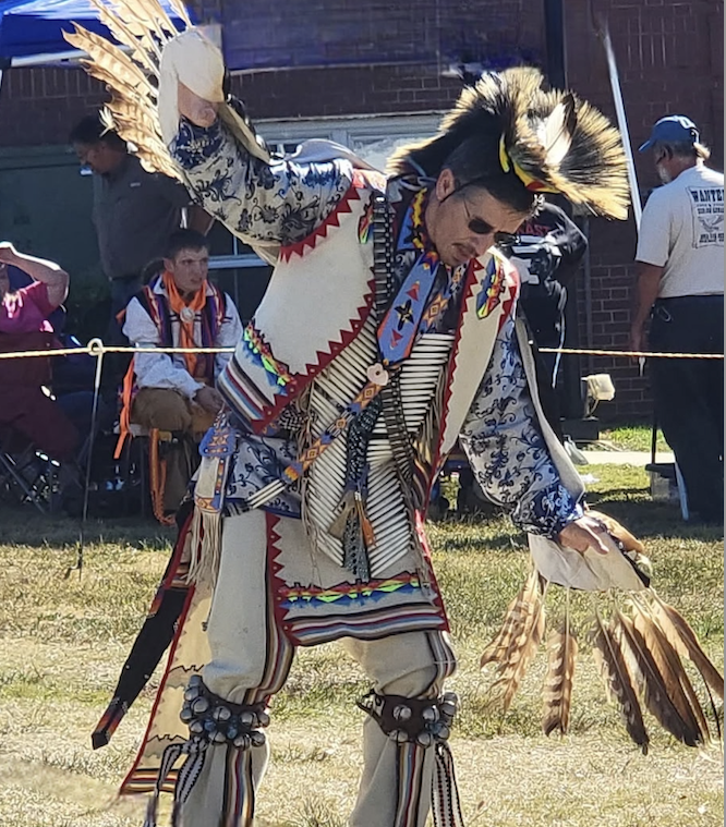 traditionally dressed indigenous man dancing in feathers