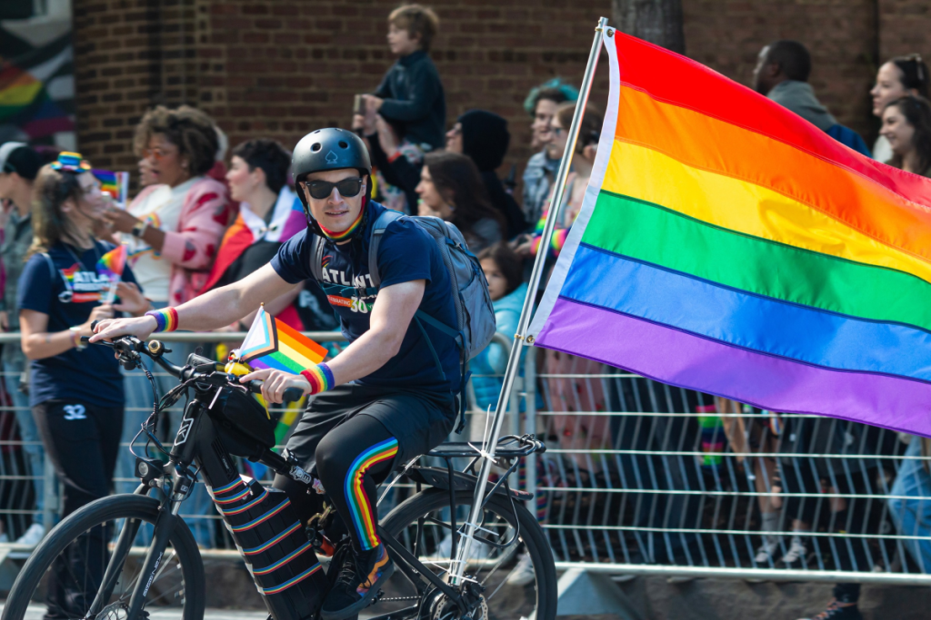 Un chico del Orgullo de Atlanta en bici con una bandera del Orgullo