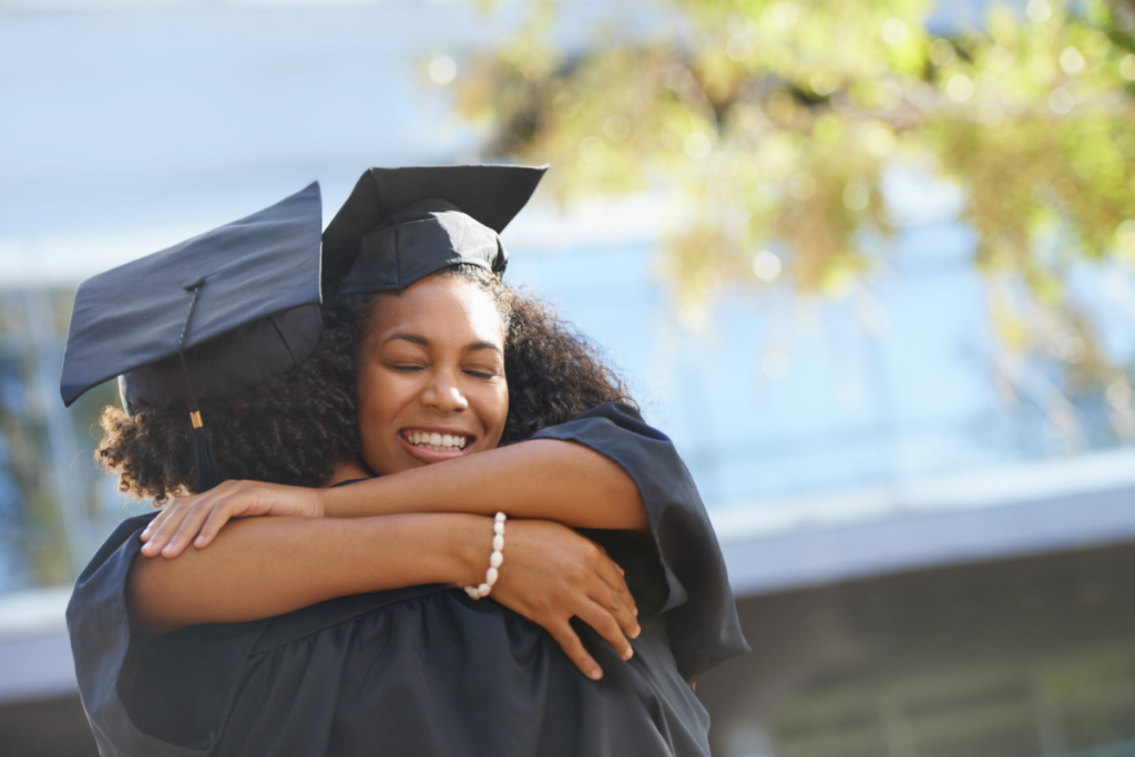 two Black college graduates hugging