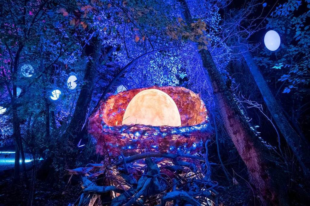 A giant, glowing orange egg is pictured in a nest made out of white lights at LUMA Enchanted.