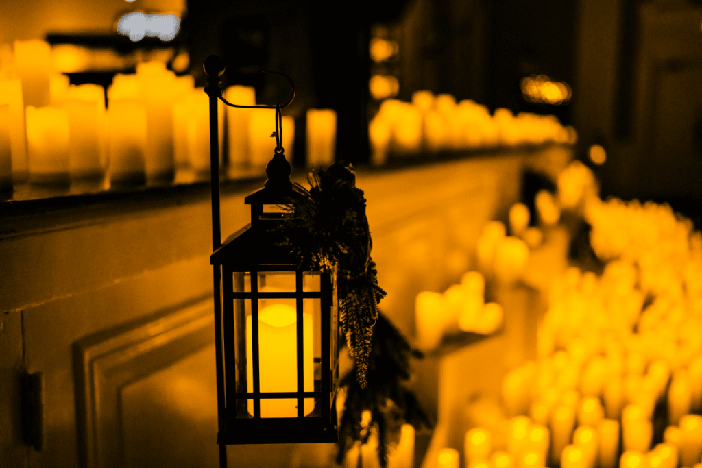 A close up of a lantern with a sea of candles in the background.