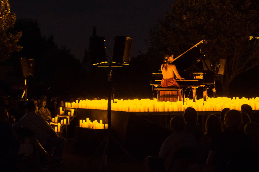 A musician playing the grand piano surrounded by a sea of candles