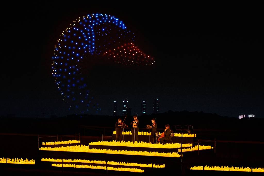 Illuminated drones fly over a string quartet