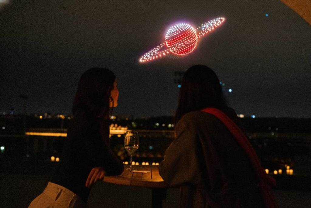 People looking up at the skyline as drones dance in a light show